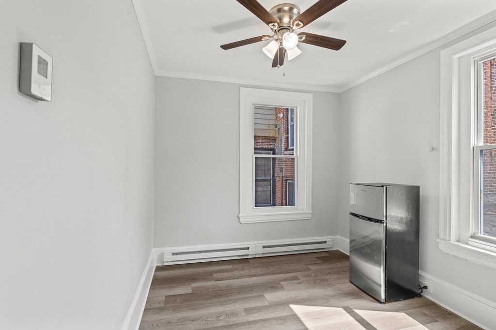 A room with a ceiling fan and a refrigerator.