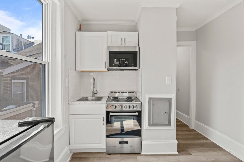 A kitchen with white cabinets and a stove top oven.