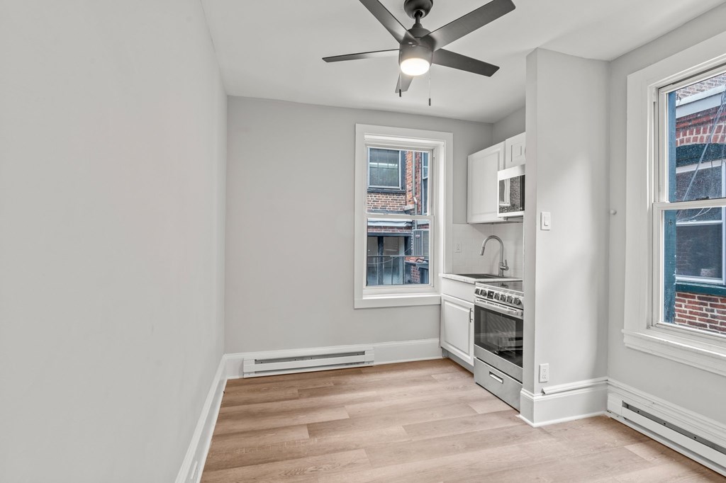 A room with a ceiling fan and a window overlooking a building.