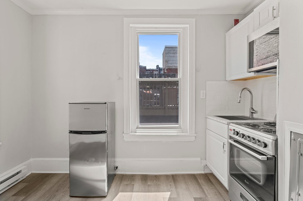 A kitchen with white appliances and a window overlooking a cityscape.
