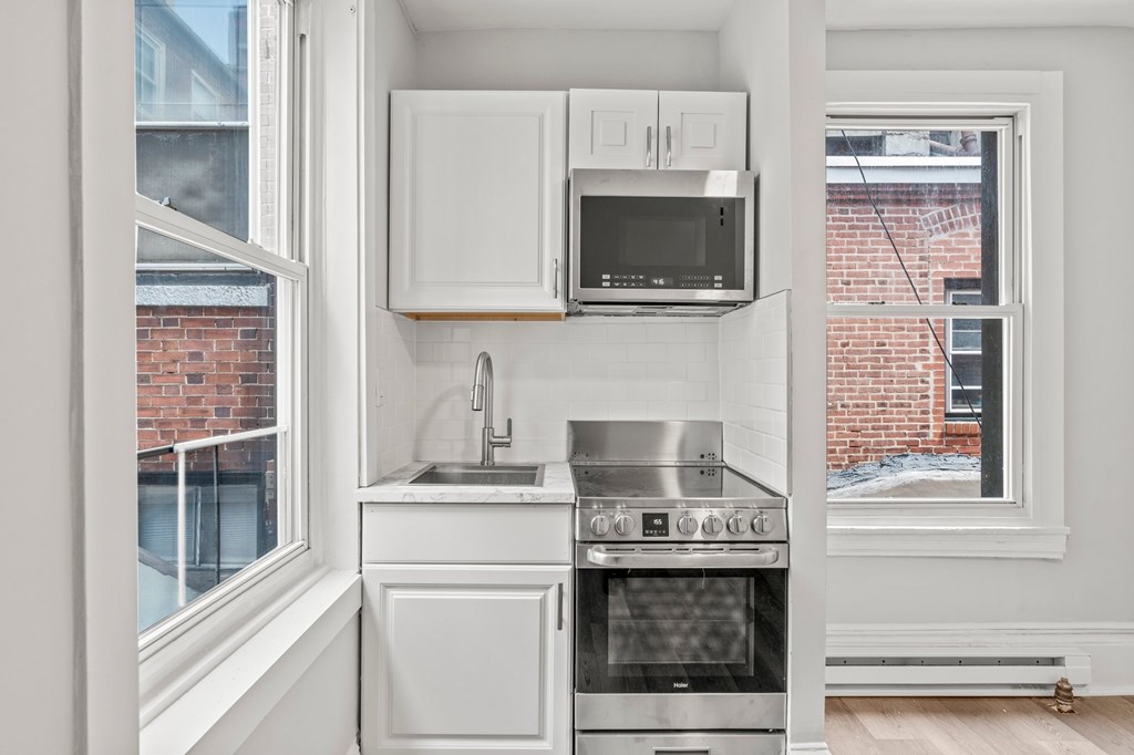 A kitchen with white cabinets and a stainless steel oven.