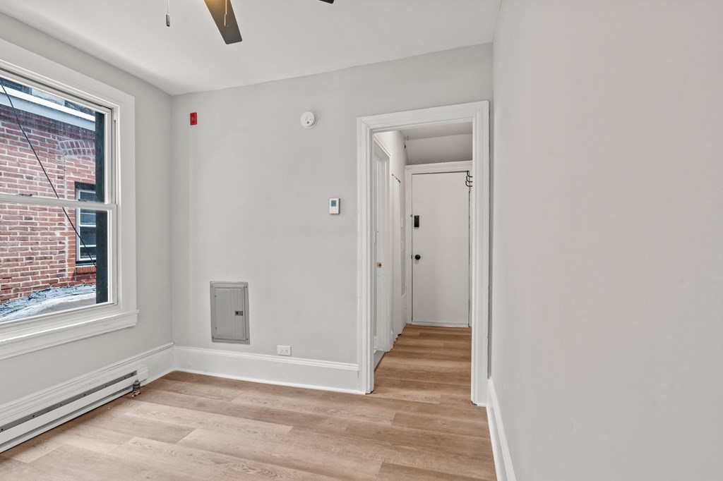 A room with a window, a door, and a wall-mounted thermostat.