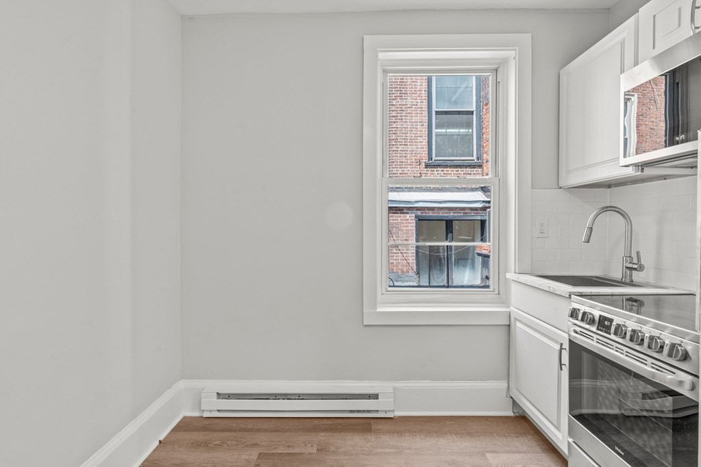 A kitchen with a white stove top oven and a window.