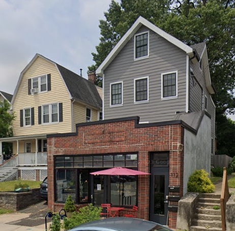 A grey house with a red umbrella in front.