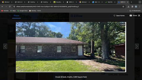 A brick house with a white door and a tree in front.