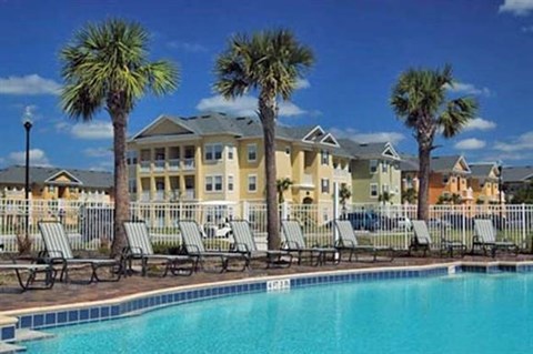 a large pool with chairs and palm trees in front of a building