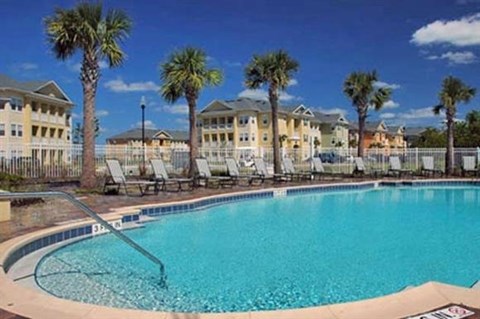 a large swimming pool with palm trees in front of a hotel