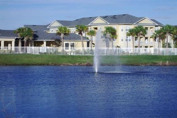 a fountain in the middle of a lake in front of a house
