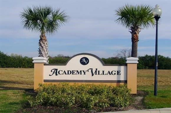 a sign village in front of palm trees