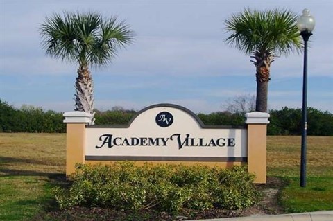 a sign village in front of palm trees