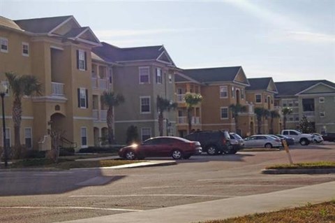 a parking lot with cars in front of an apartment building