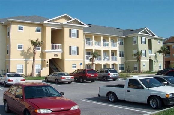 a parking lot filled with cars in front of an apartment building