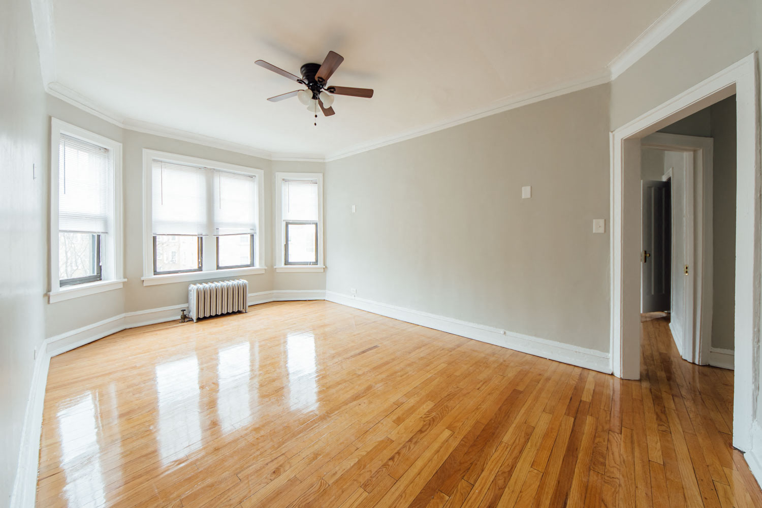 an empty living room with wood floors and a ceiling fan