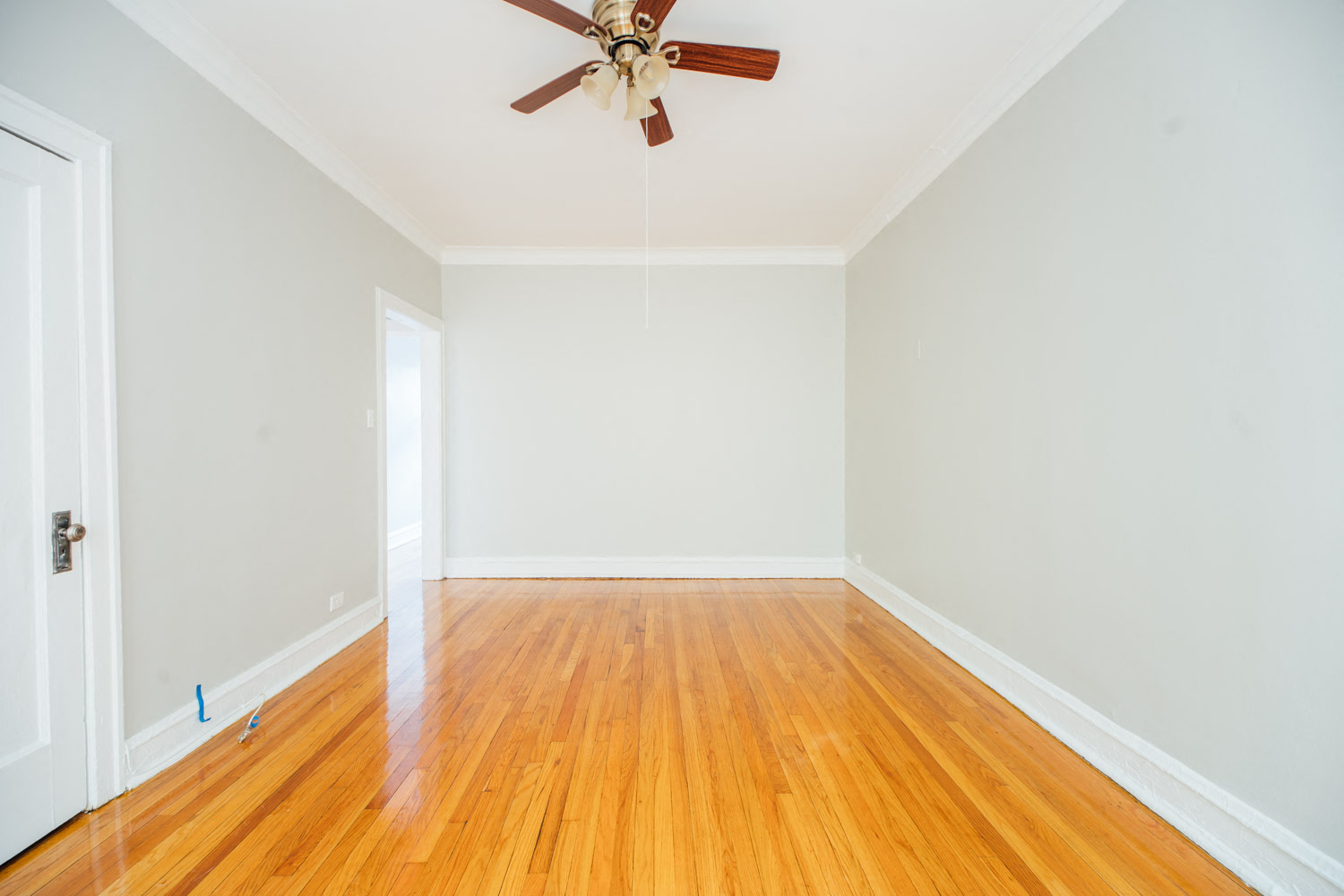 an empty room with wood floors and a ceiling fan