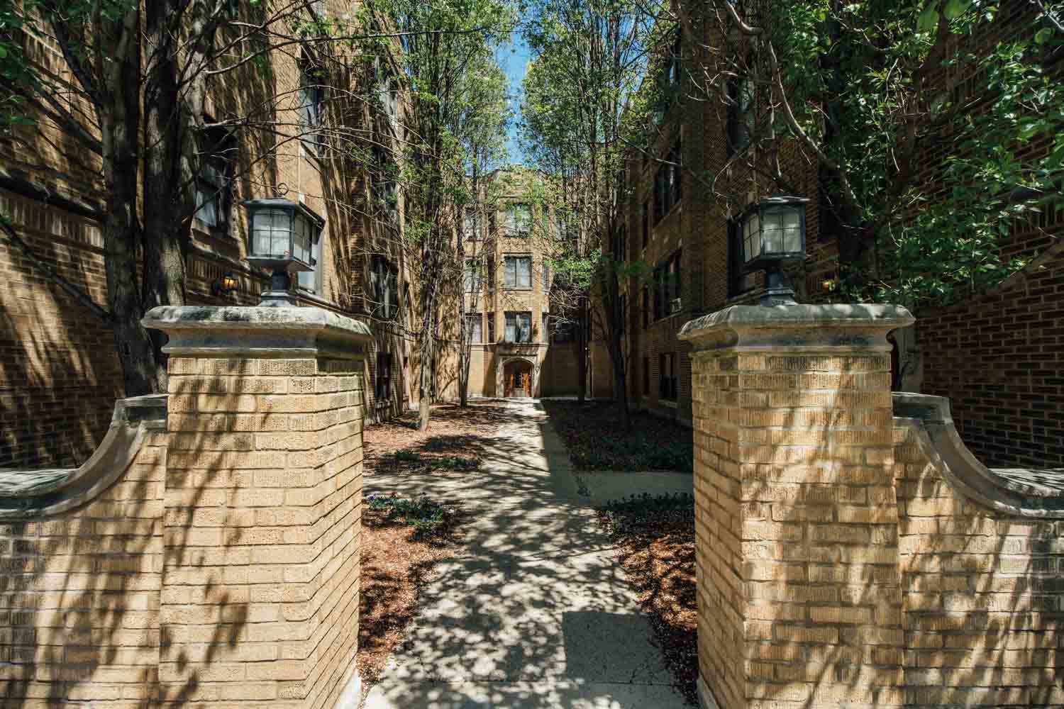 a pathway between two brick pillars and trees