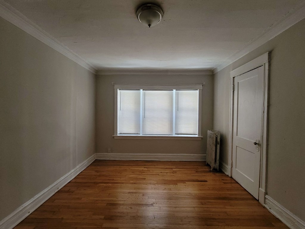 a small room with a window and wooden floors