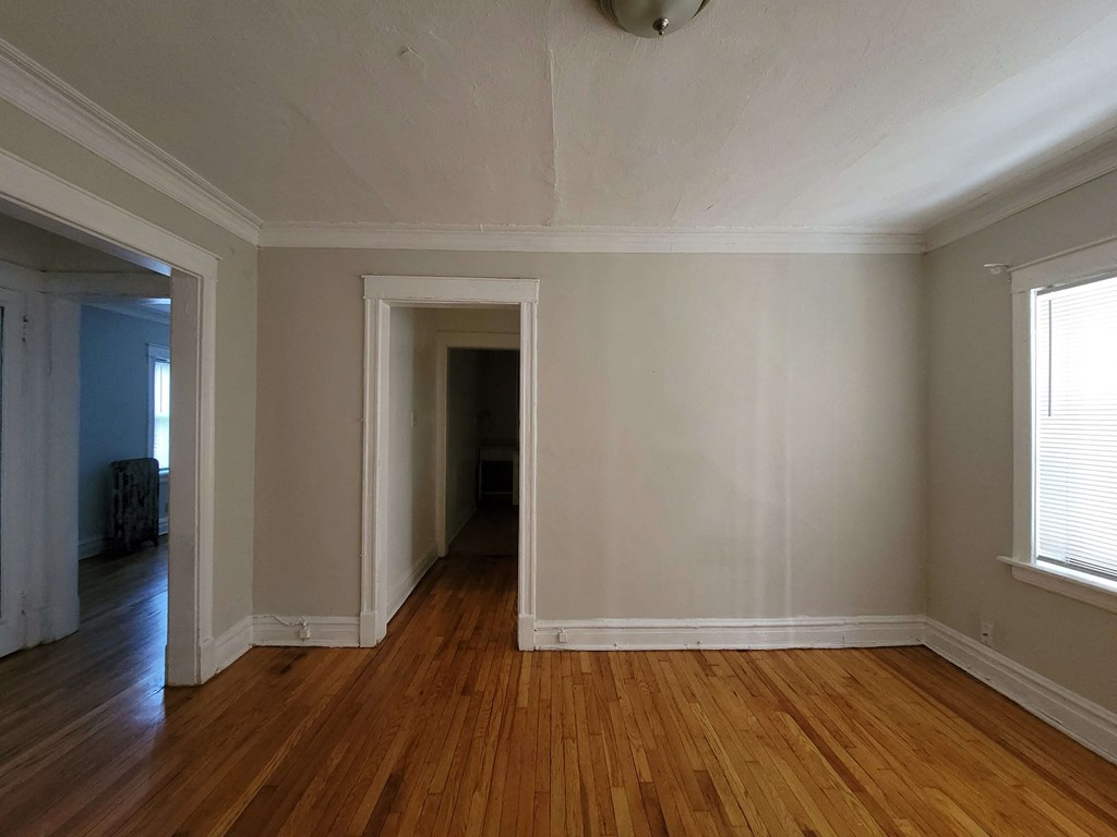 an empty living room with wood floors and white walls