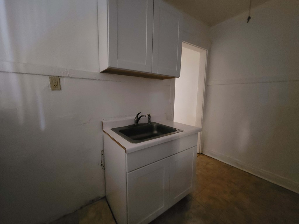 an empty kitchen with a sink and white cabinets