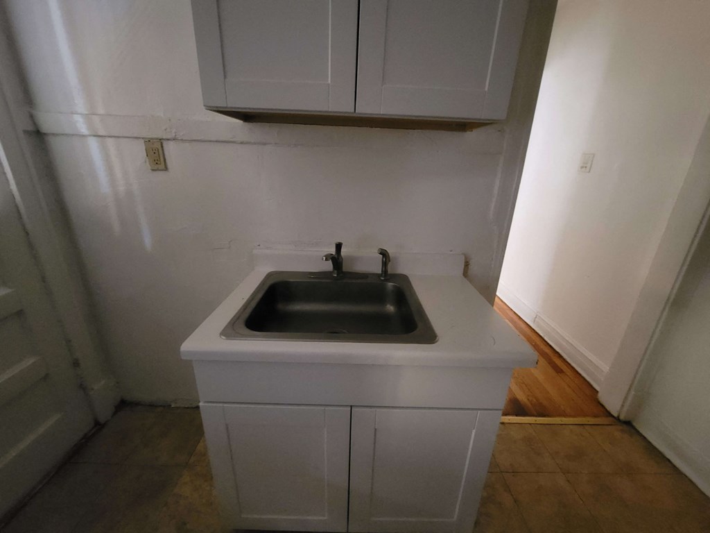 an empty kitchen with a sink and white cabinets