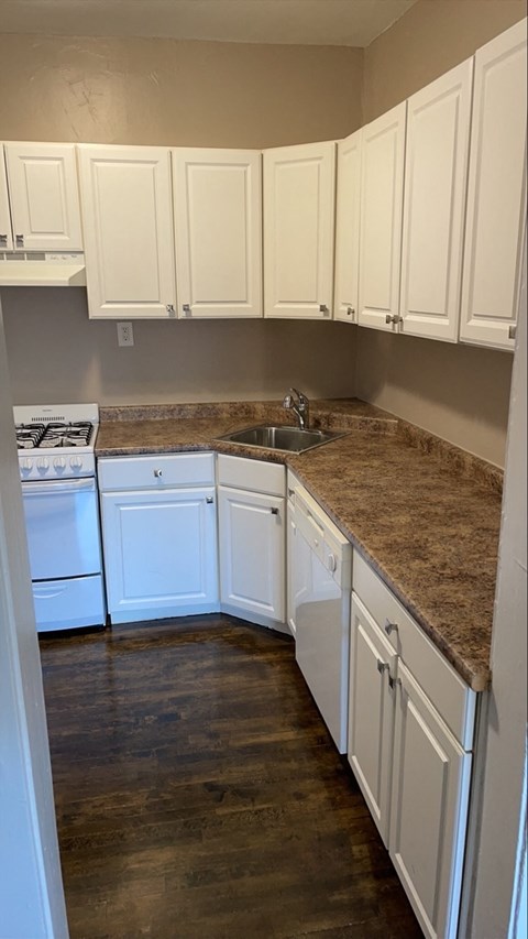 a kitchen with white cabinets and marble counter tops