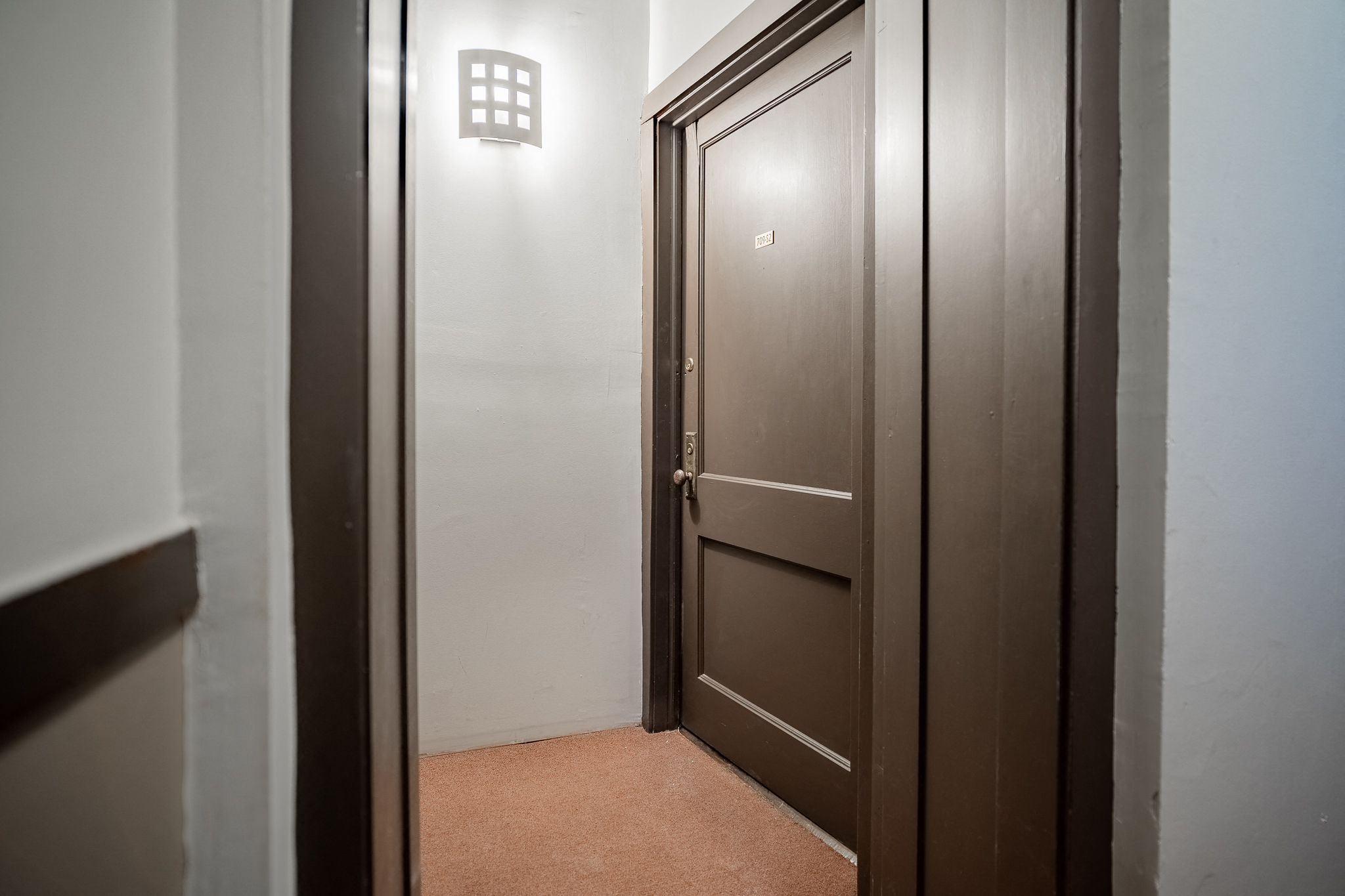 a door to a room with a white wall and a brown door