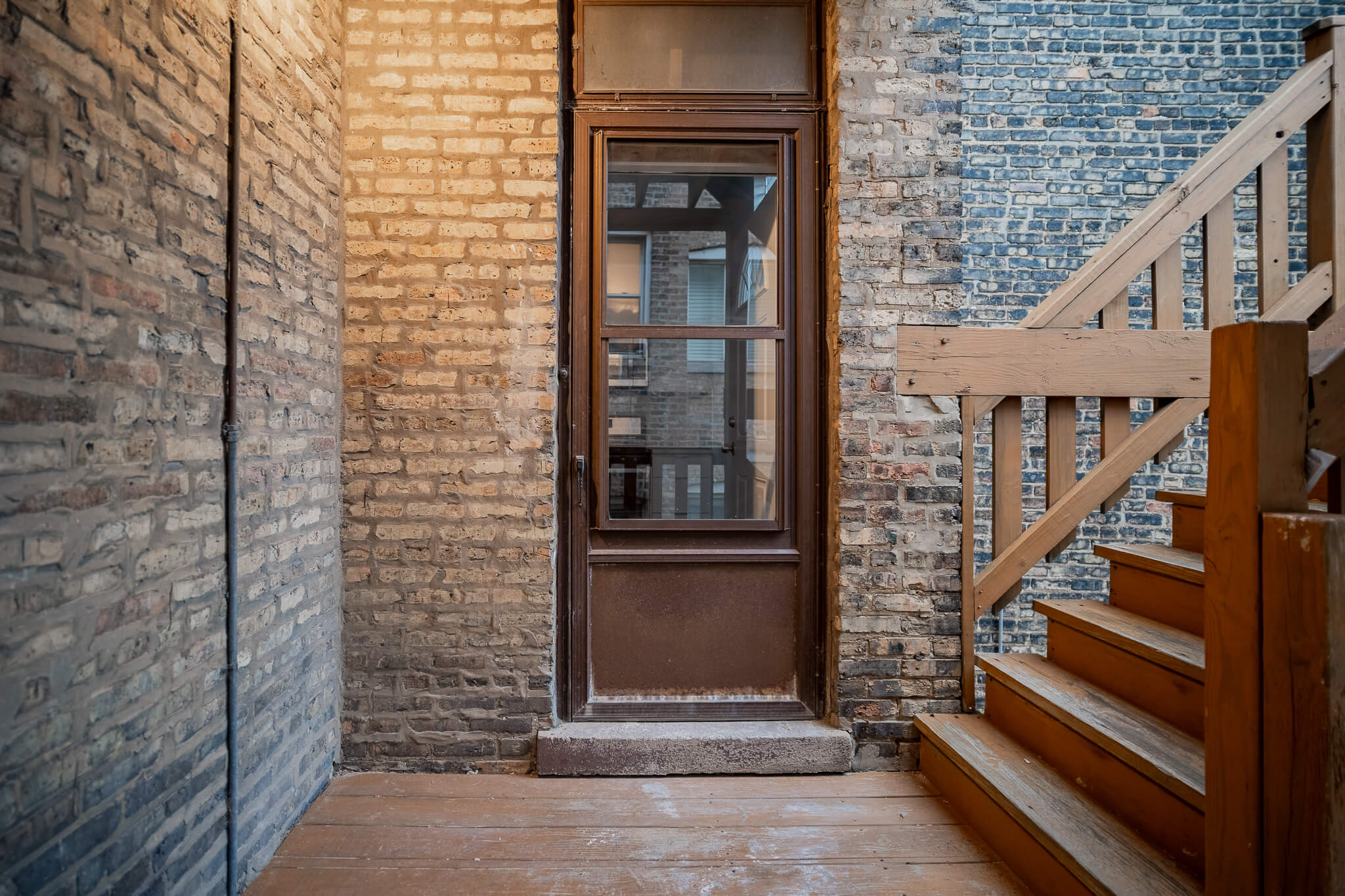 the front door of a brick house with a brown door and stairs