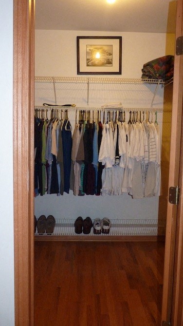 a closet with a rack of clothes and shoes in it