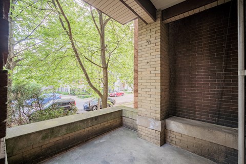 the view from the front porch of a brick apartment building with trees and a street
