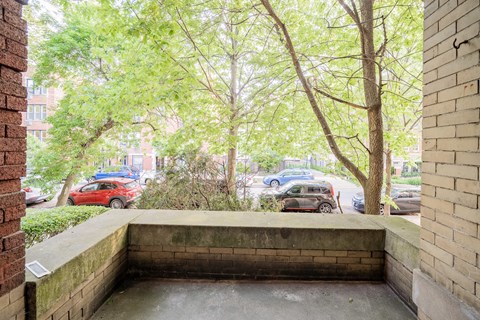 the entrance of a building with trees and cars on the street