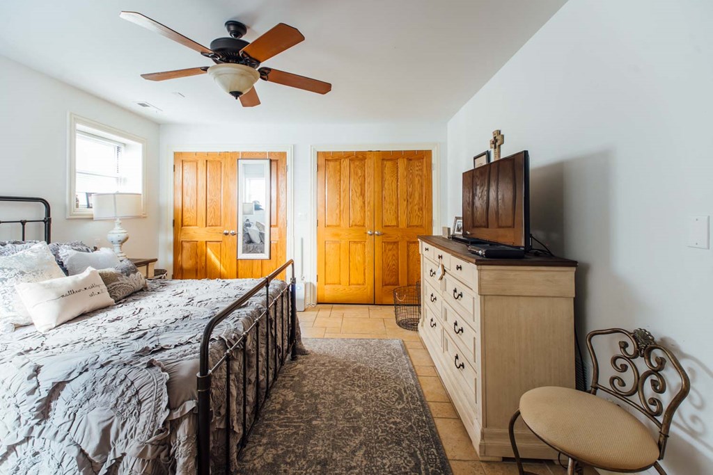 a bedroom with a bed and a ceiling fan and a tv