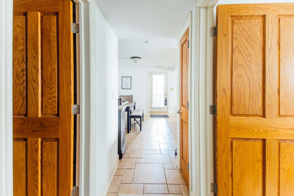 a hallway with wooden doors leading into a kitchen and a dining room