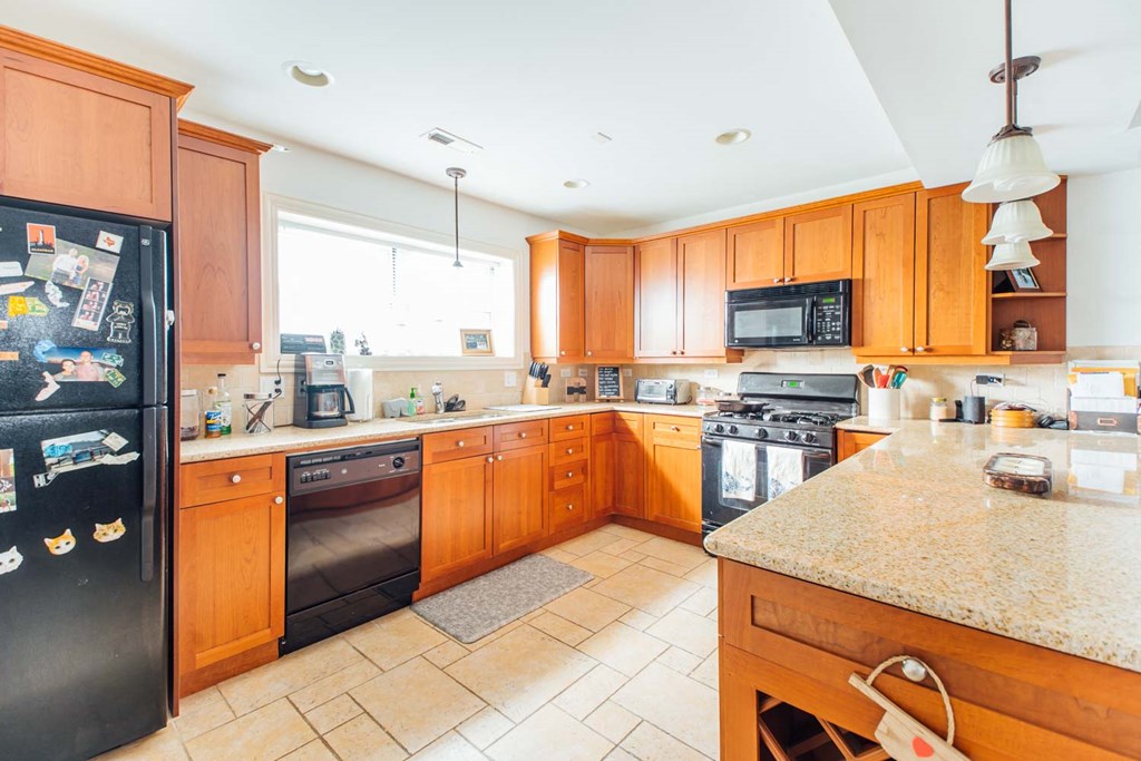 a kitchen with wooden cabinets and a black refrigerator