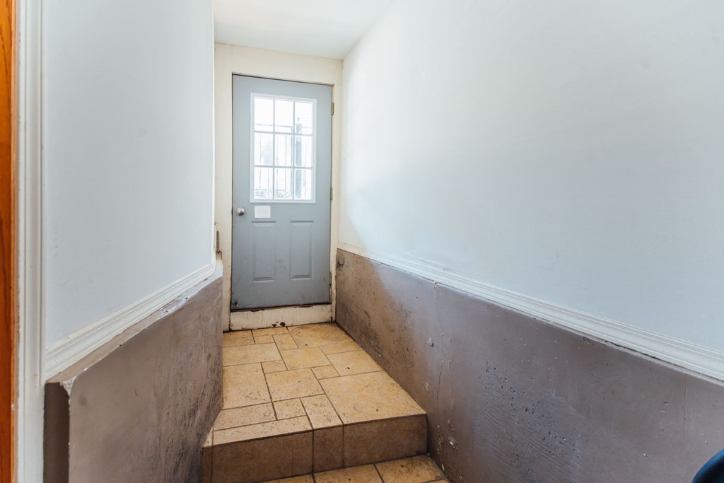 a door in a room with a tiled floor and white walls