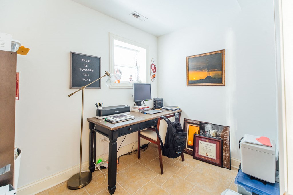 the home office has a desk with a computer and a window