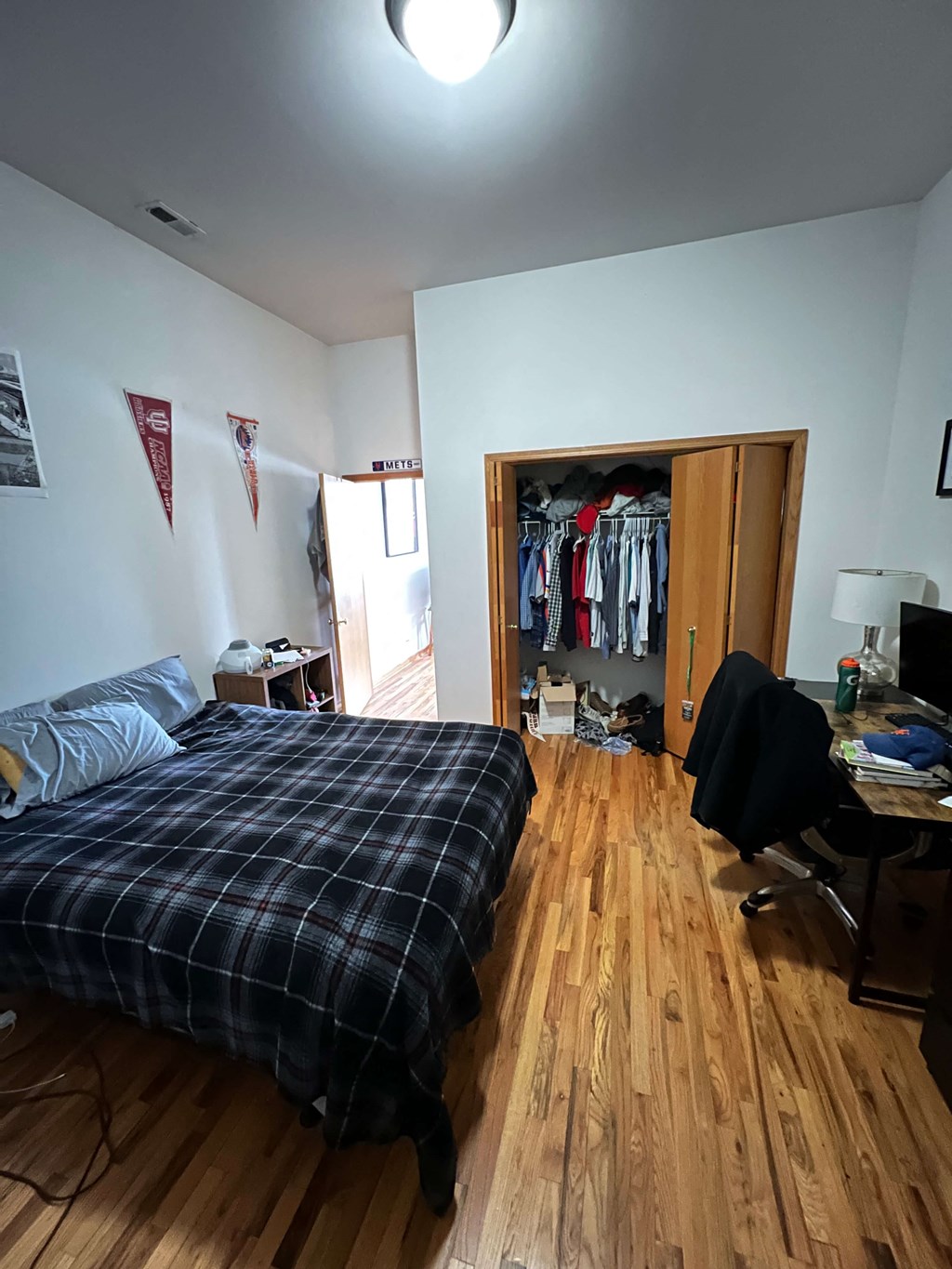 a bedroom with a bed and a closet with clothes in it