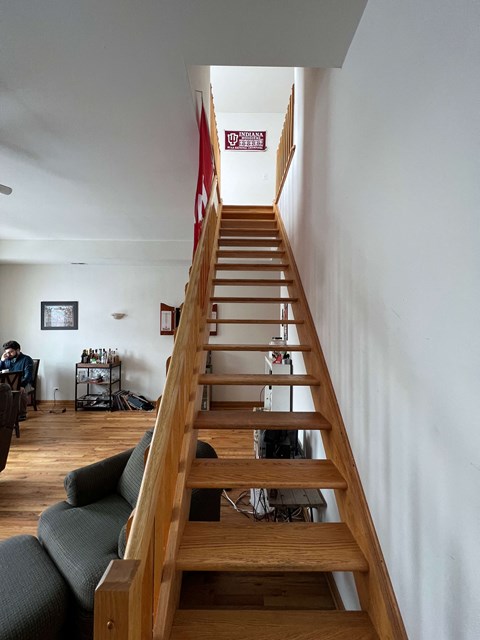 a wooden staircase in a living room with a black couch