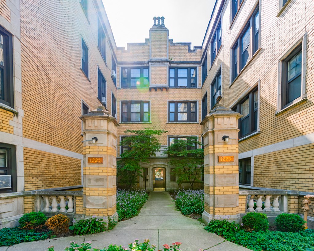a courtyard between two tall brick buildings with a sidewalk