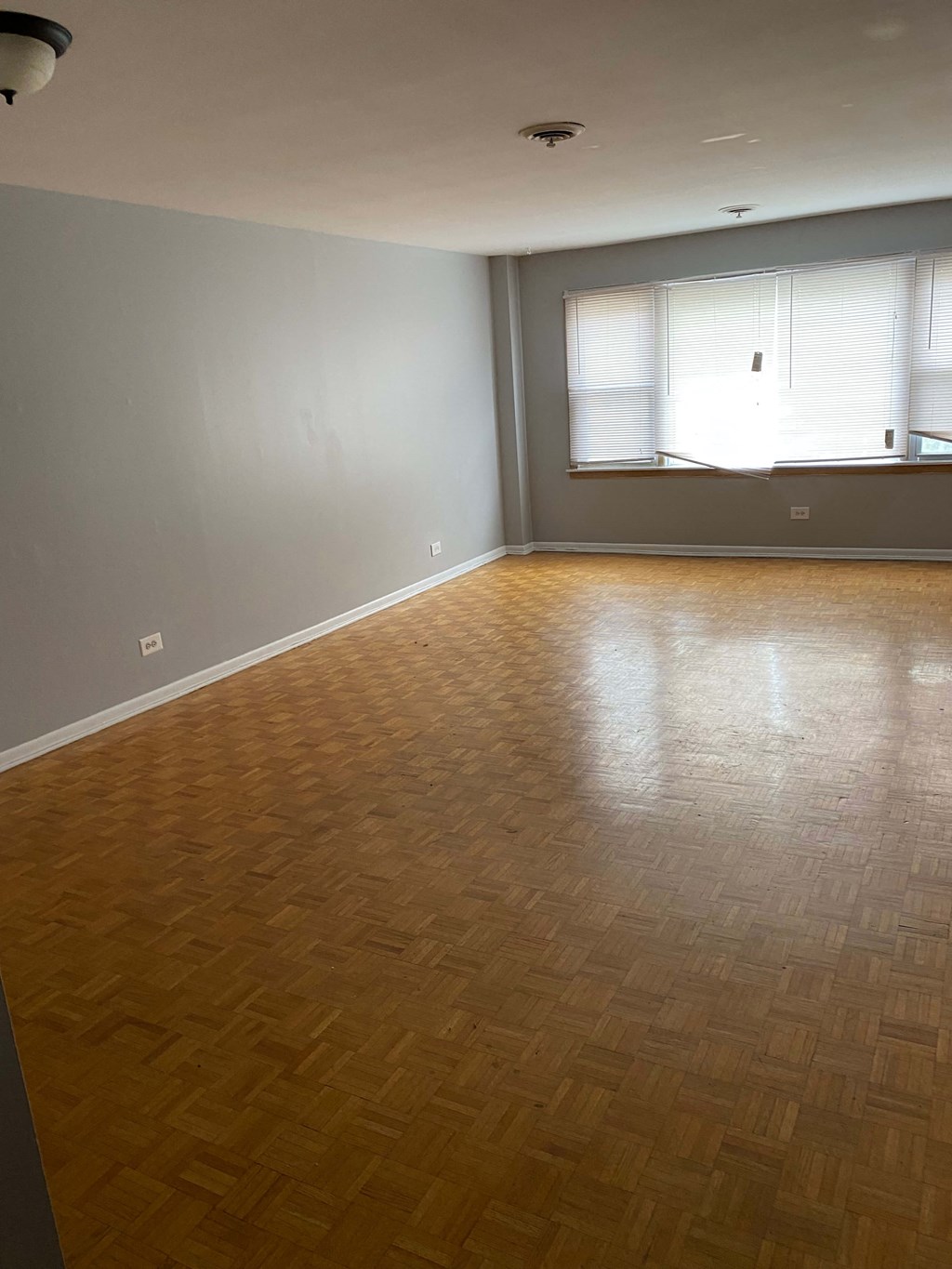 an empty living room with wood floors and a window