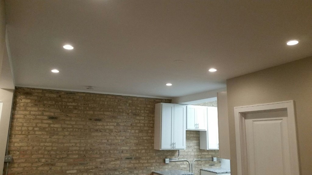 a kitchen with a brick wall and white cabinets