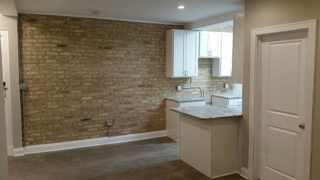 a small kitchen with a sink and a brick wall