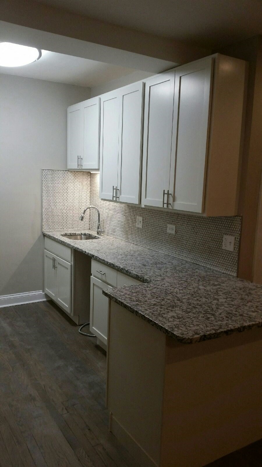 an empty kitchen with marble counter tops and white cabinets