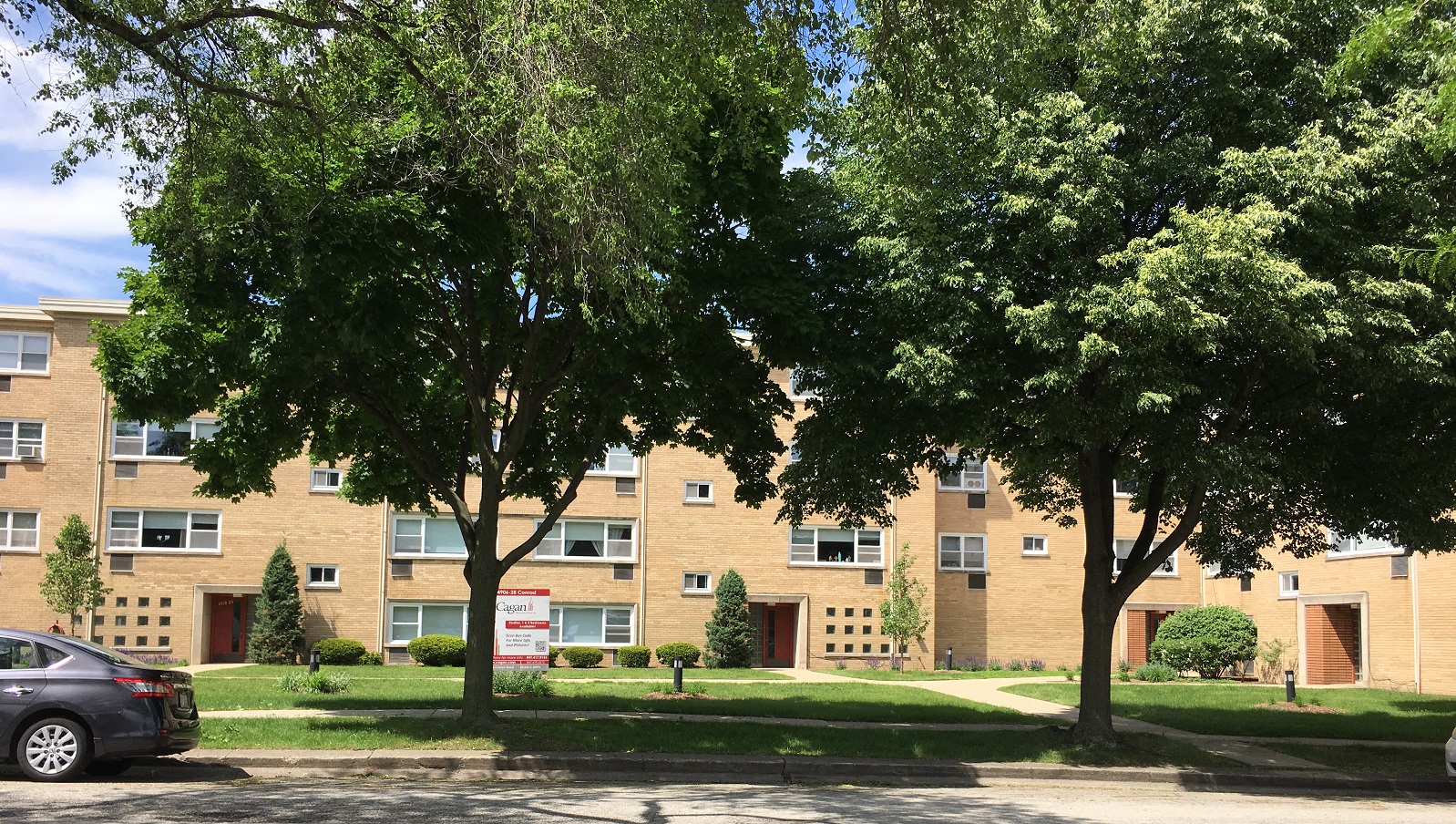 the outlook of an apartment building with trees in front of it