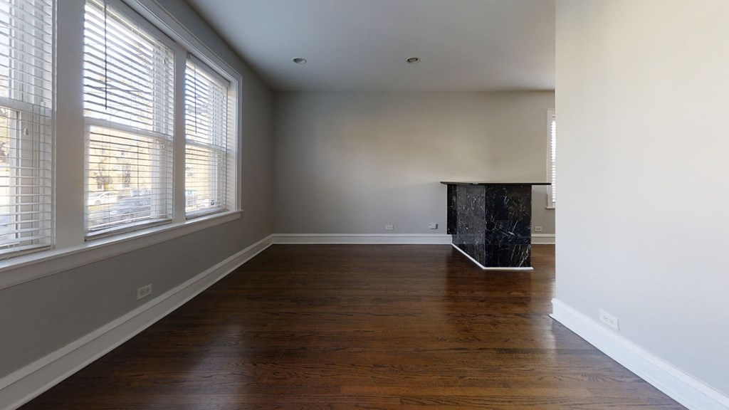 an empty living room with wood floors and large windows