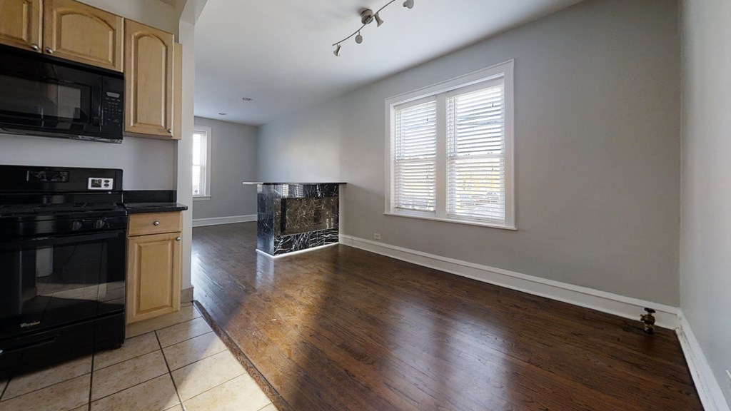 an empty kitchen and living room with wood floors and a fireplace