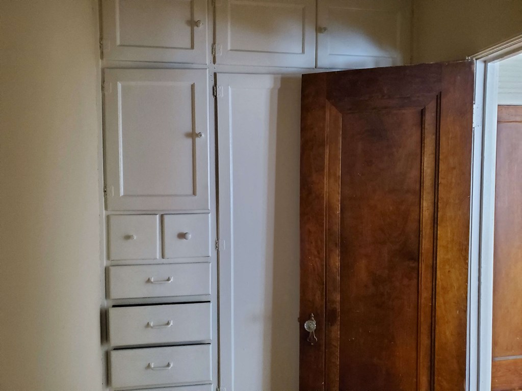 a closet with white drawers and a wooden door