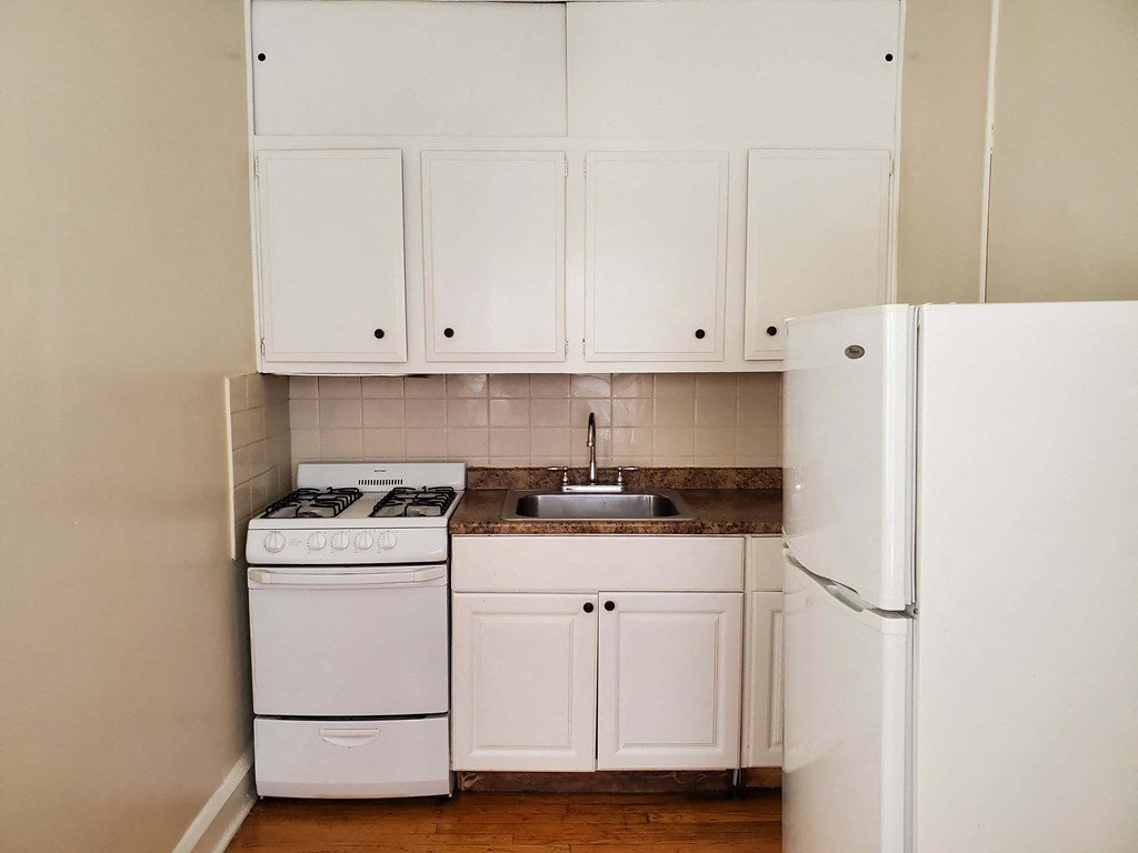 an empty kitchen with white appliances and white cabinets