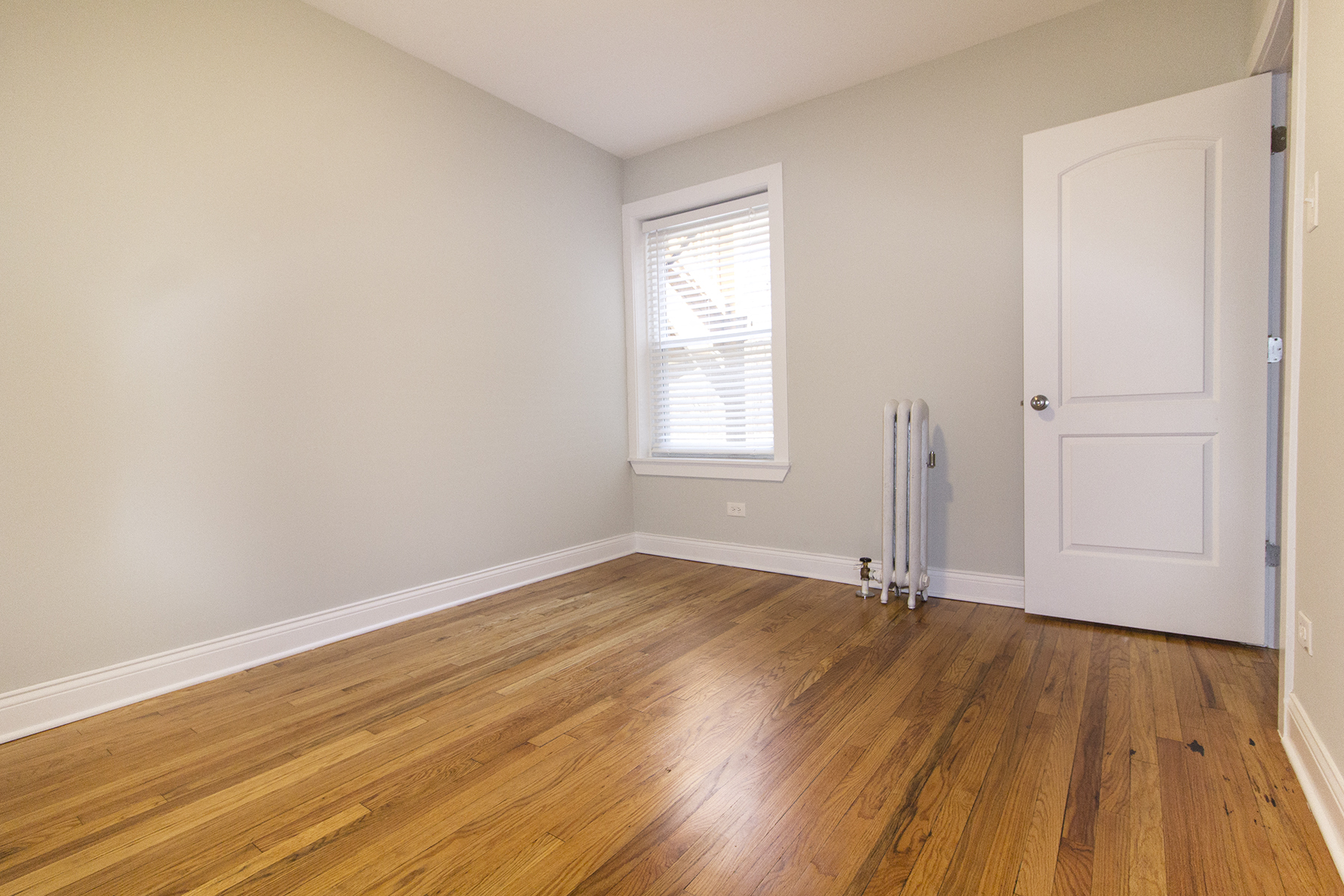 an empty room with wooden floors and a white door