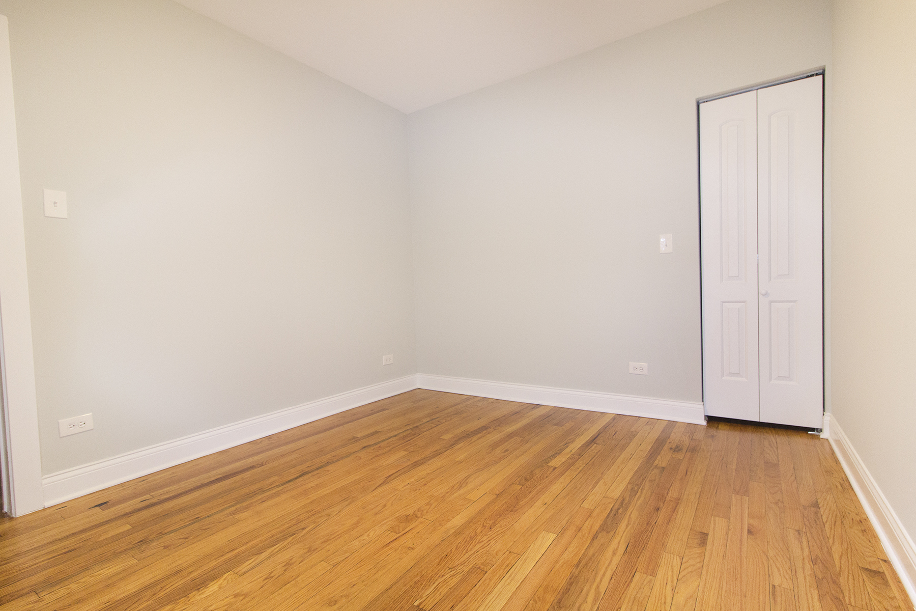 an empty room with wooden floors and a white door