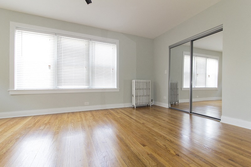 an empty living room with a hard wood floor and a mirror