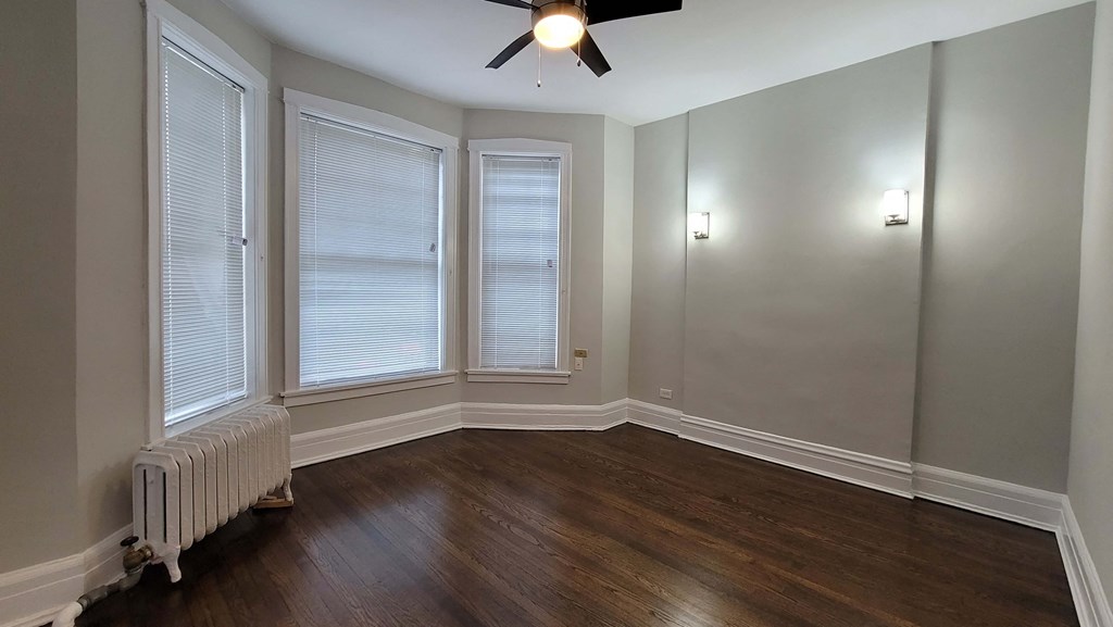 a living room with a ceiling fan and three windows